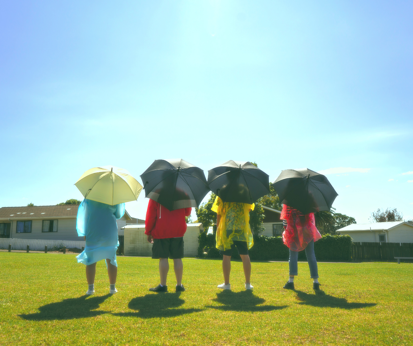 The Potential for Rain New Zealand theatre: people standing with umbrellas in sun